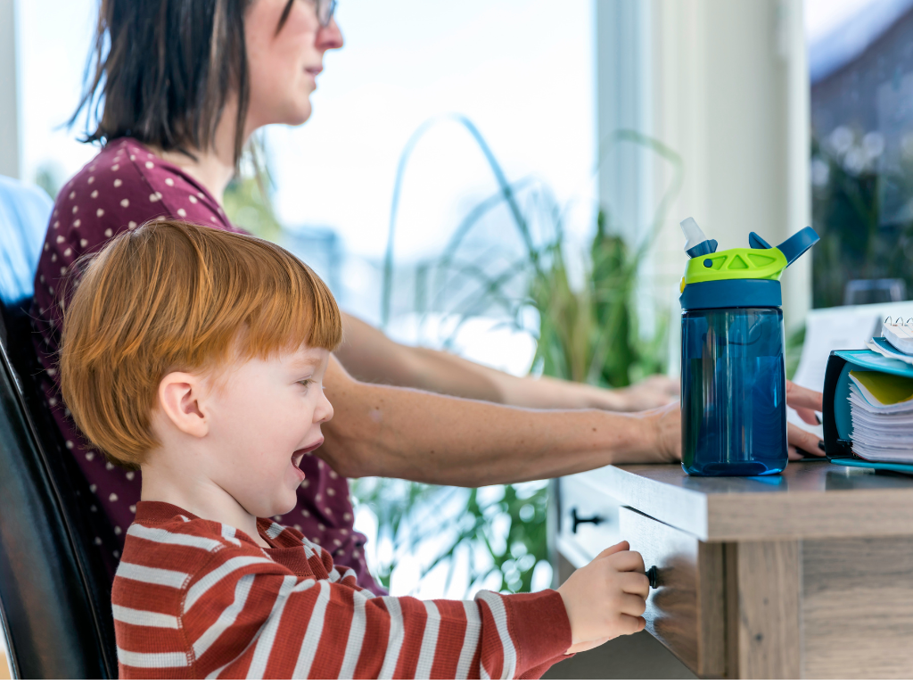 Woman working from home with a child playing besides her